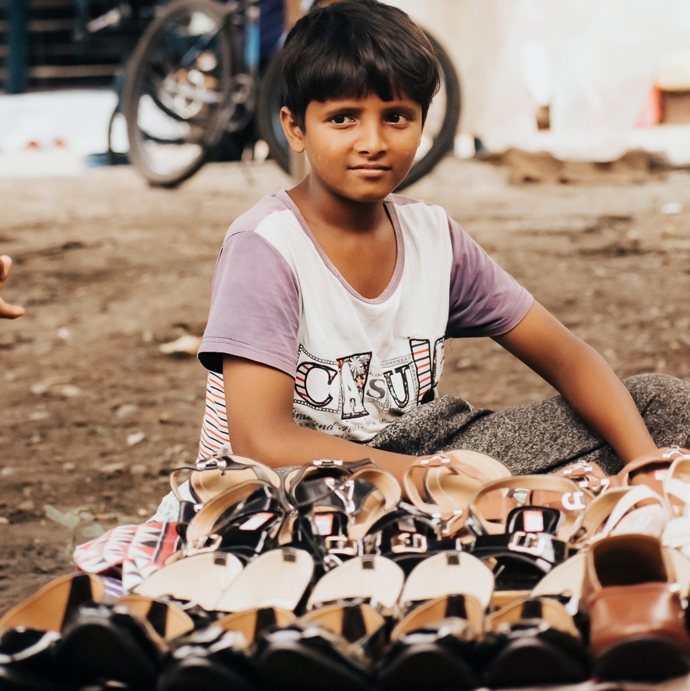A child selling shoes at a market stall.
