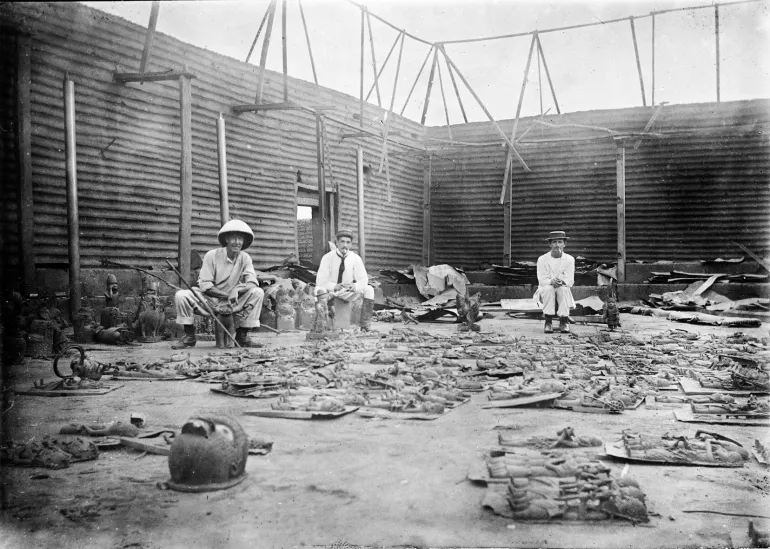 The interior of the Benin king’s compound burned during the siege of Benin City in 1897, with bronze plaques in the foreground, cementing political and economic inequalities.
