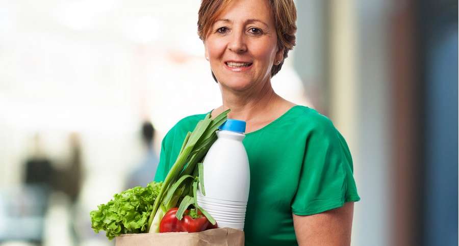 portrait of a mature woman carrying a shopping bag with food