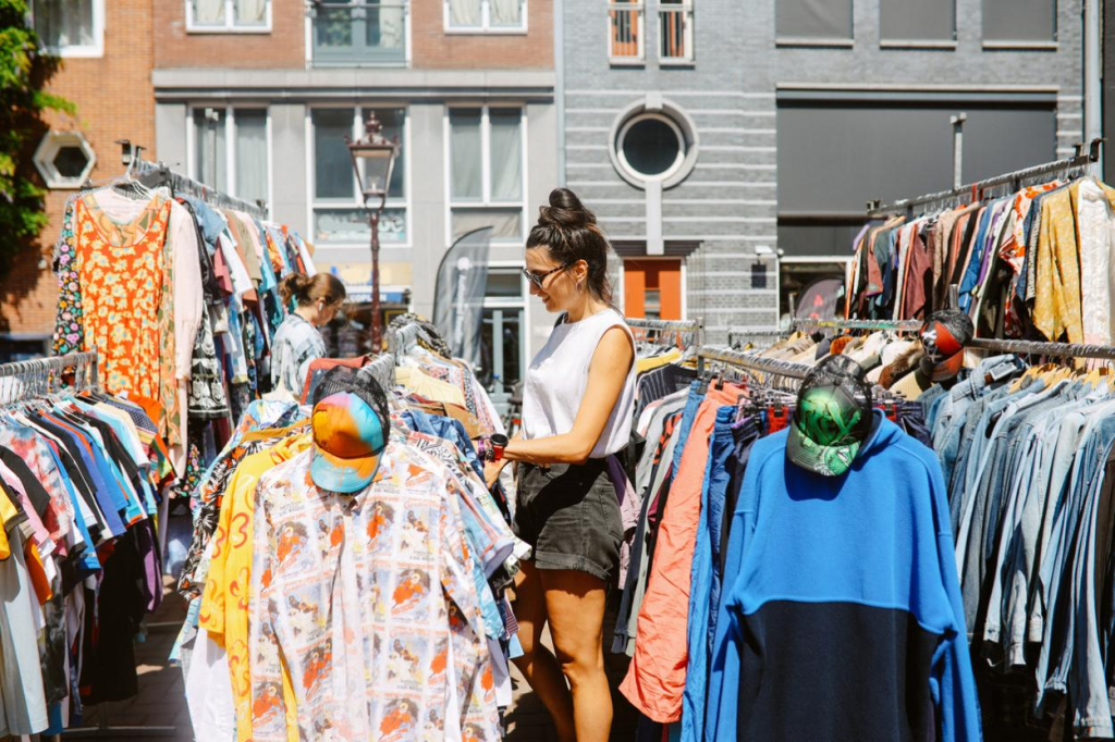 An open-air flea market filled with second-hand items of clothing. This is popular way for people to engage in thrifting.